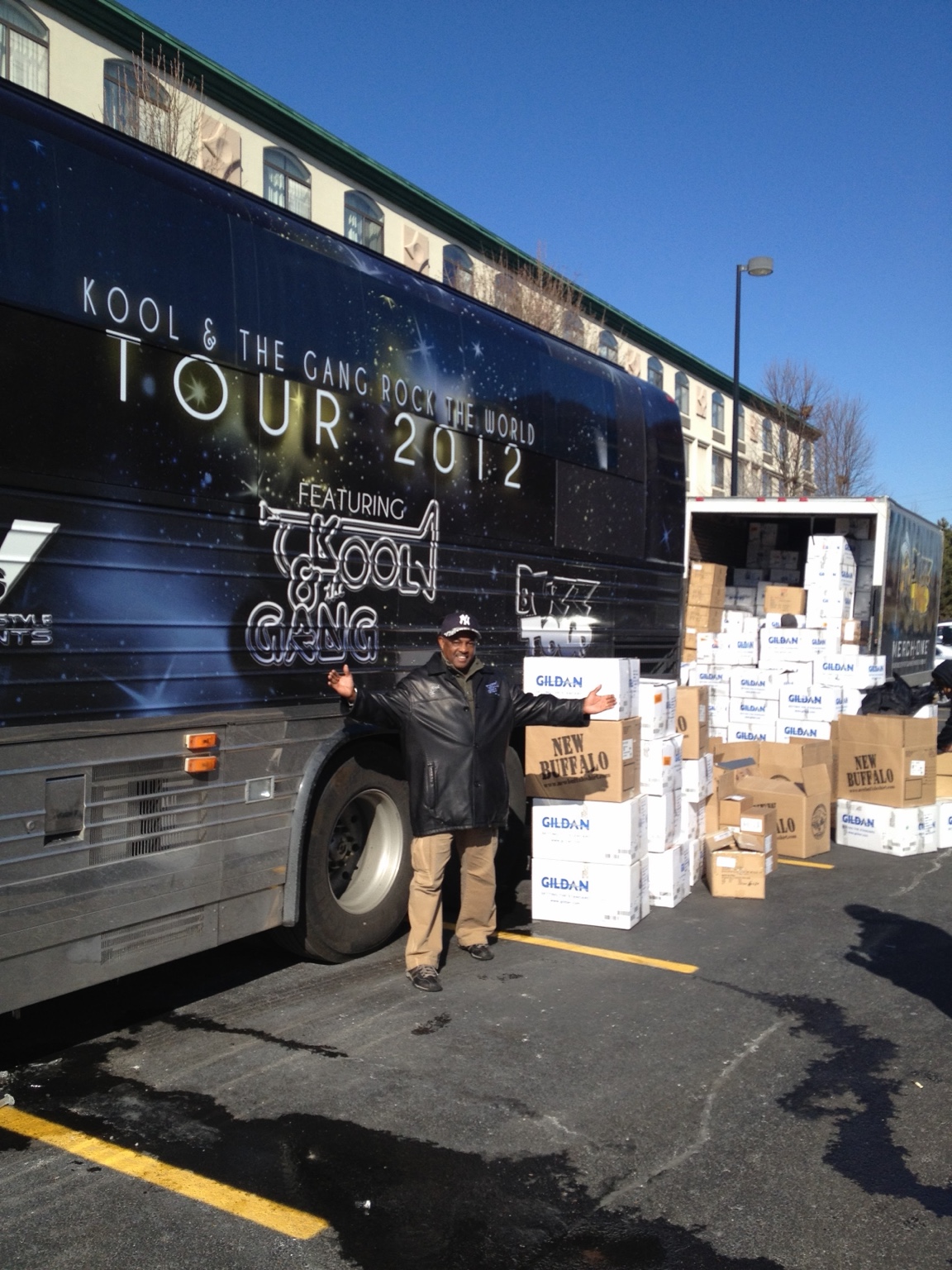 Kool of Kool & The Gang in front of the Rock The World Tour 2012 bus, with tour merchandise boxes being unloaded